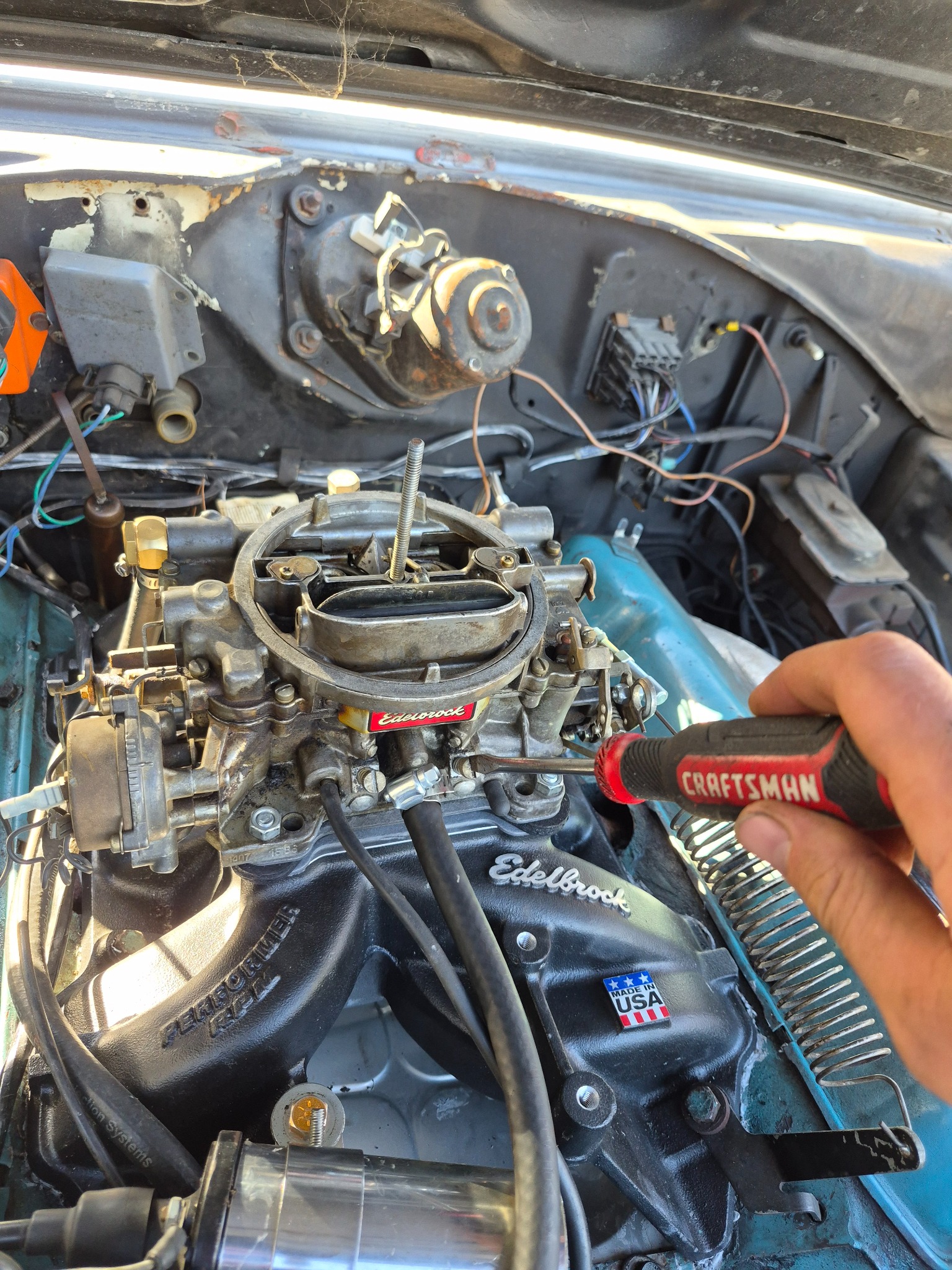 Carburetor being adjusted with a screwdriver