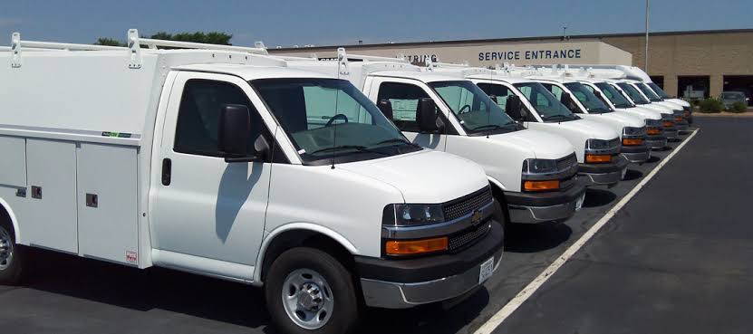A fleet of white commercial service vans