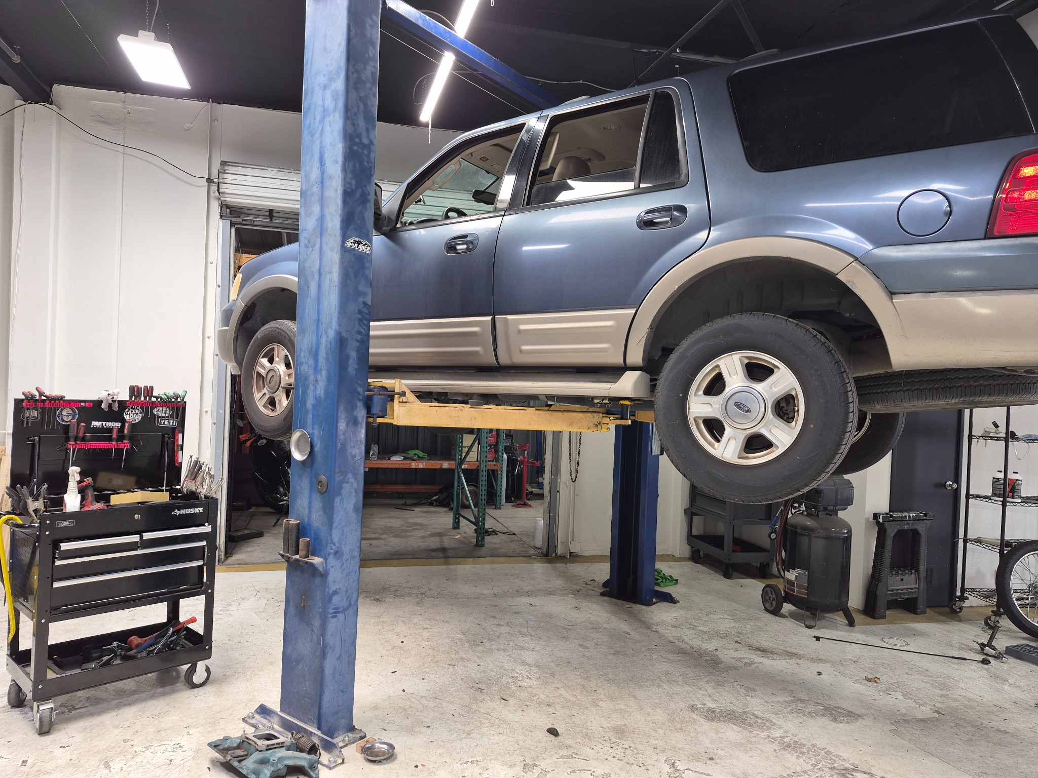 Blue SUV raised on a lift inside SP Automotive